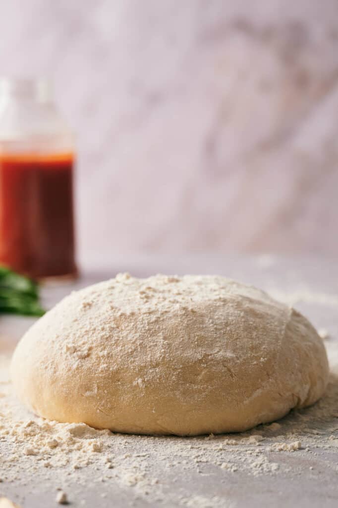 Homemade pizza dough on a lightly floured surface.