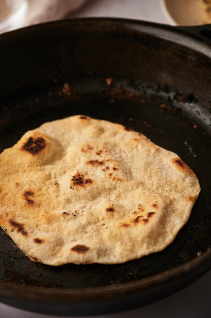 Flour tortilla cooking in a skillet.