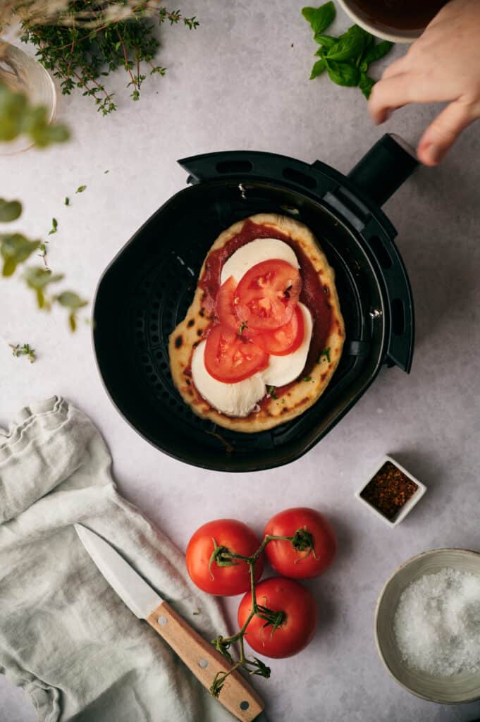 Uncooked flat bread pizza in the air fryer basket,