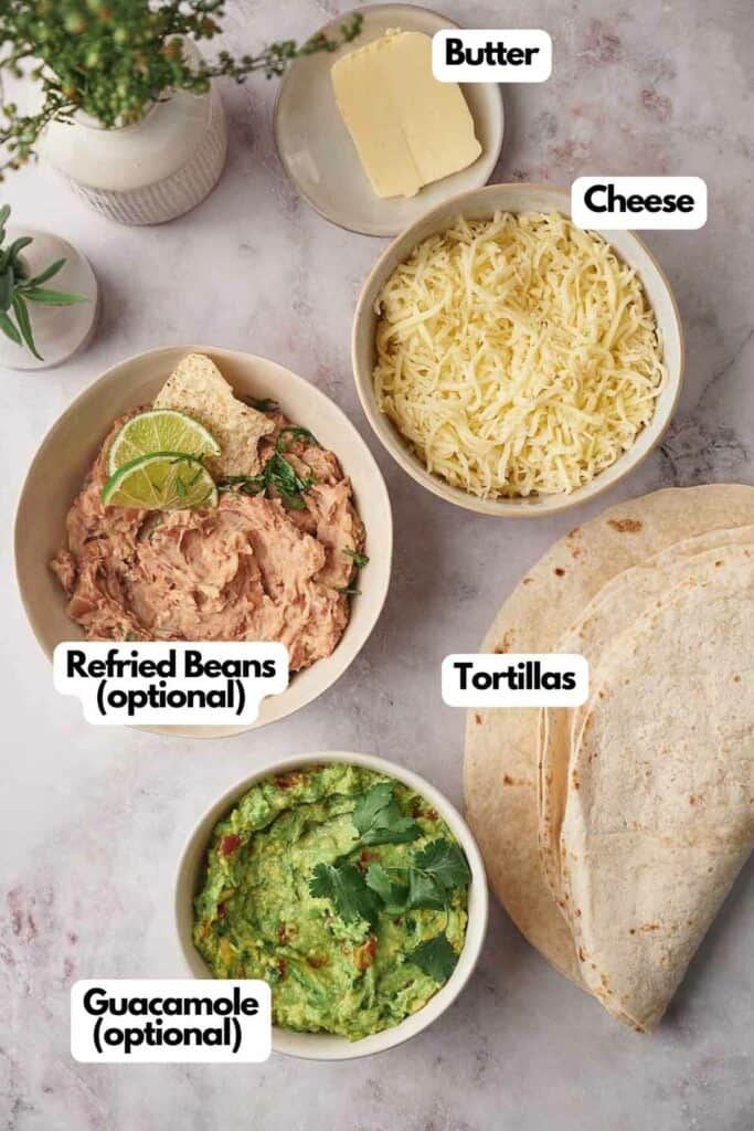 Ingredients needed; butter, shredded cheese, flour tortillas, refried beans (optional), and guacamole (optional).