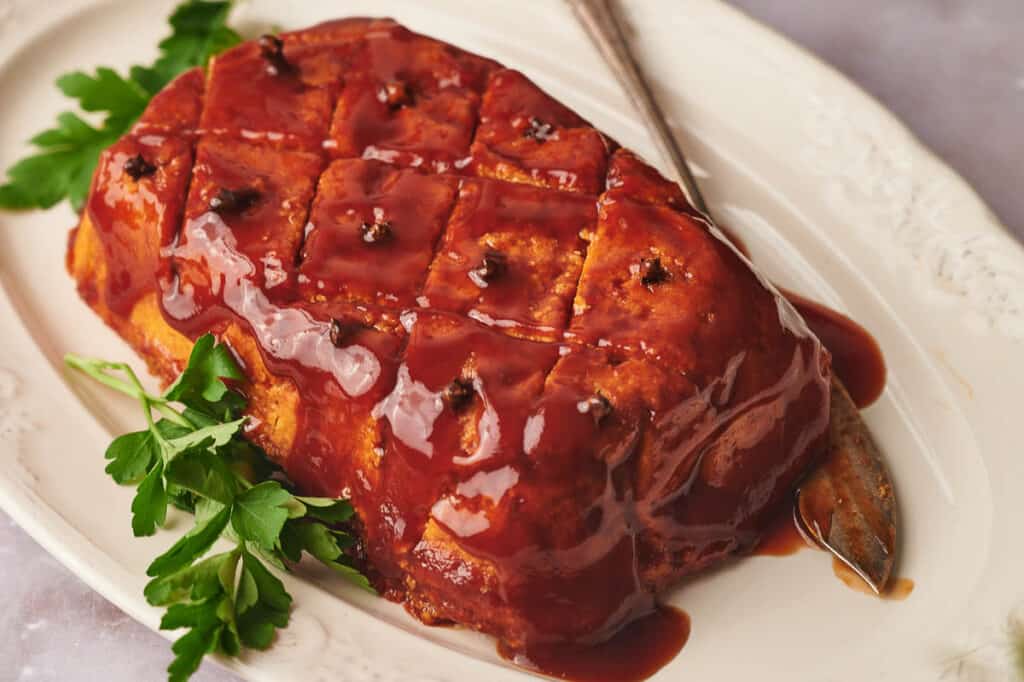 Air fryer vegan ham on a serving plate with a knife, ready to eat.