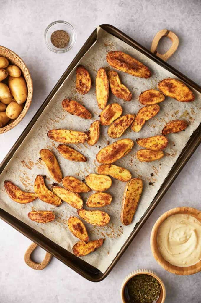 A baking sheet with cooked potatoes on it.