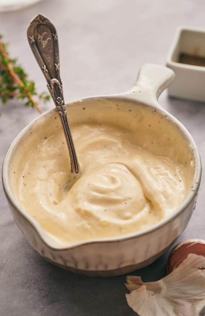 Garlic aioli in a serving bowl with a spoon.