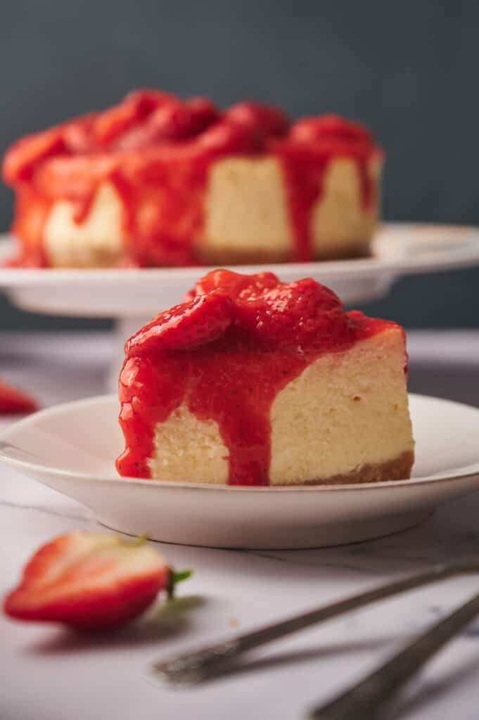 A slice of cheesecake with strawberries on a plate.