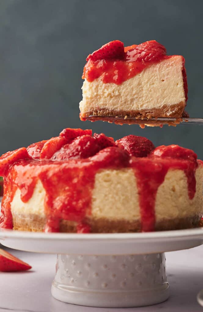 A slice of strawberry cheesecake being served on a cake slice.