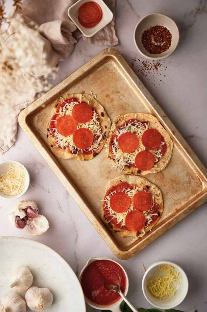 Uncooked tortilla pizzas with veggie pepperoni slices.
