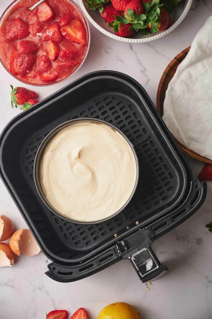 Cheesecake uncooked in an air fryer basket.