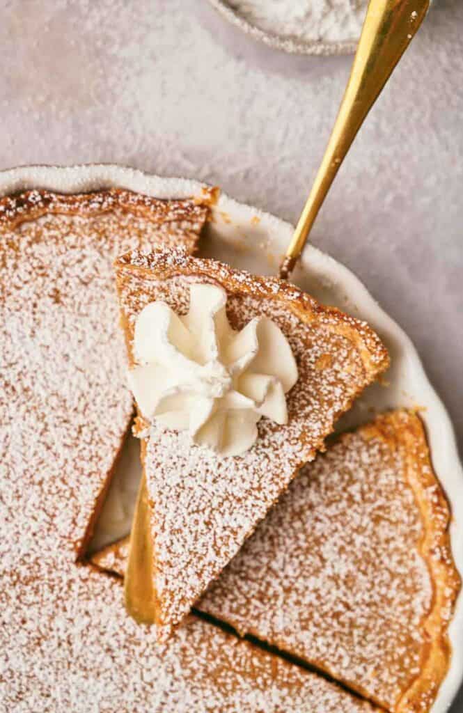 A slice of delicious homemade cinnamon pie with a swirl of whipped cream on top.