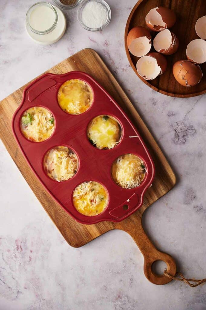 Whisked egg poured into the muffin cups.