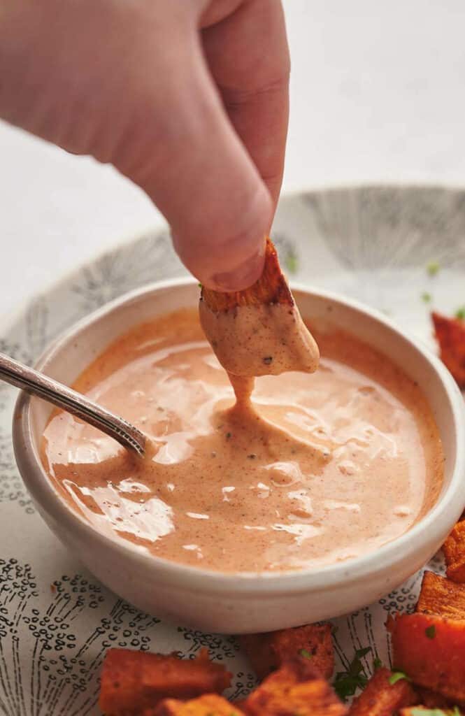 Someone dipping sweet potato in dipping sauce.