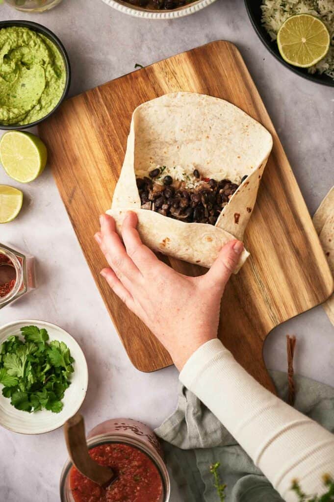 Someone folding a filled tortilla.