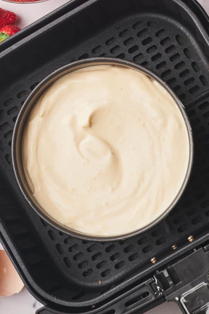 Raw cheesecake in an air fryer basket.
