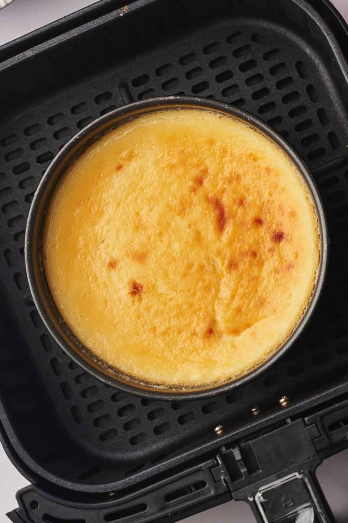 Cooked cheesecake in an air fryer basket.