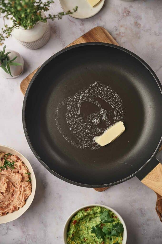 A skillet wit butter melting in it.