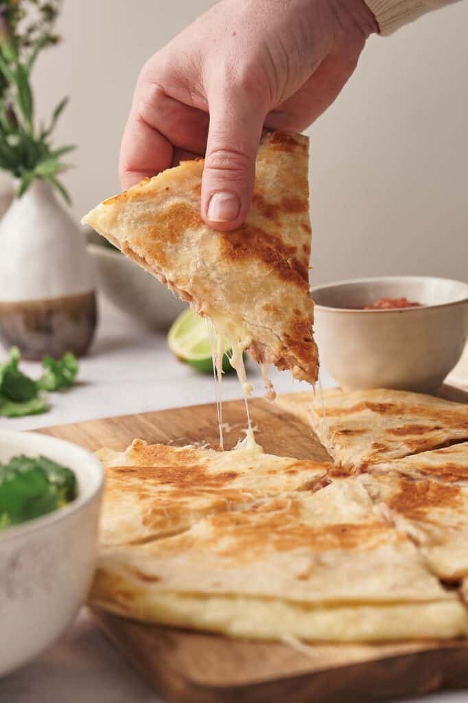 Someone grabbing a slice of chees quesadilla.