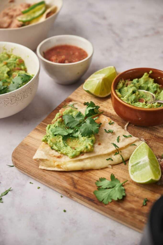 A slice of cheese quesadilla with guacamole on top.