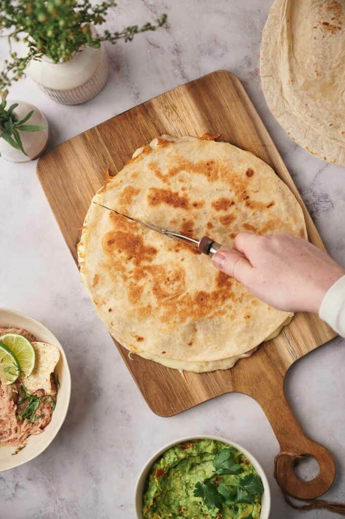Someone slicing a quesadilla.