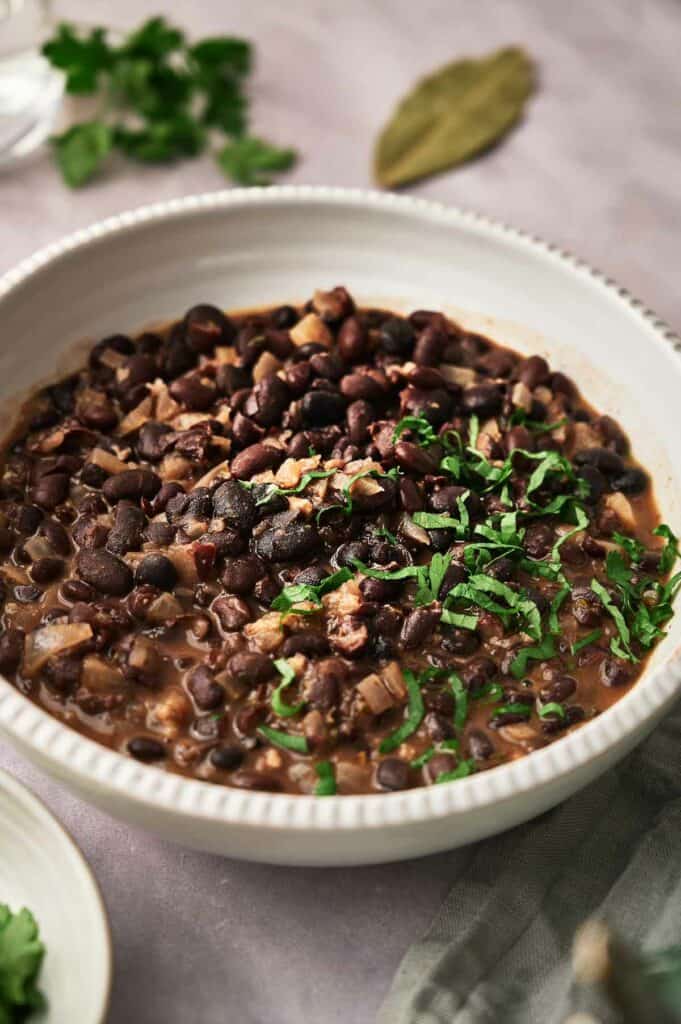 A bowl of freshly cooked Chipotle black beans with shredded parsley on top.