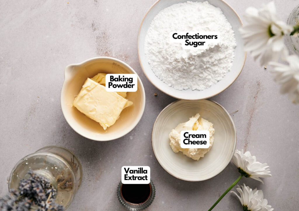 Overhead view of labeled bowls containing baking powder, vanilla extract, cream cheese, and confectioners sugar on a light surface with white flowers&mdash;perfect for your next pie crust recipe.
