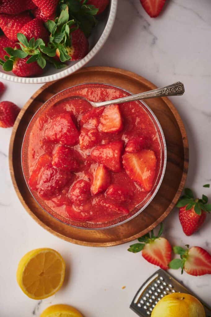 Strawberry sauce in a bowl, a tablespoon rests in it ready to scoop it out.