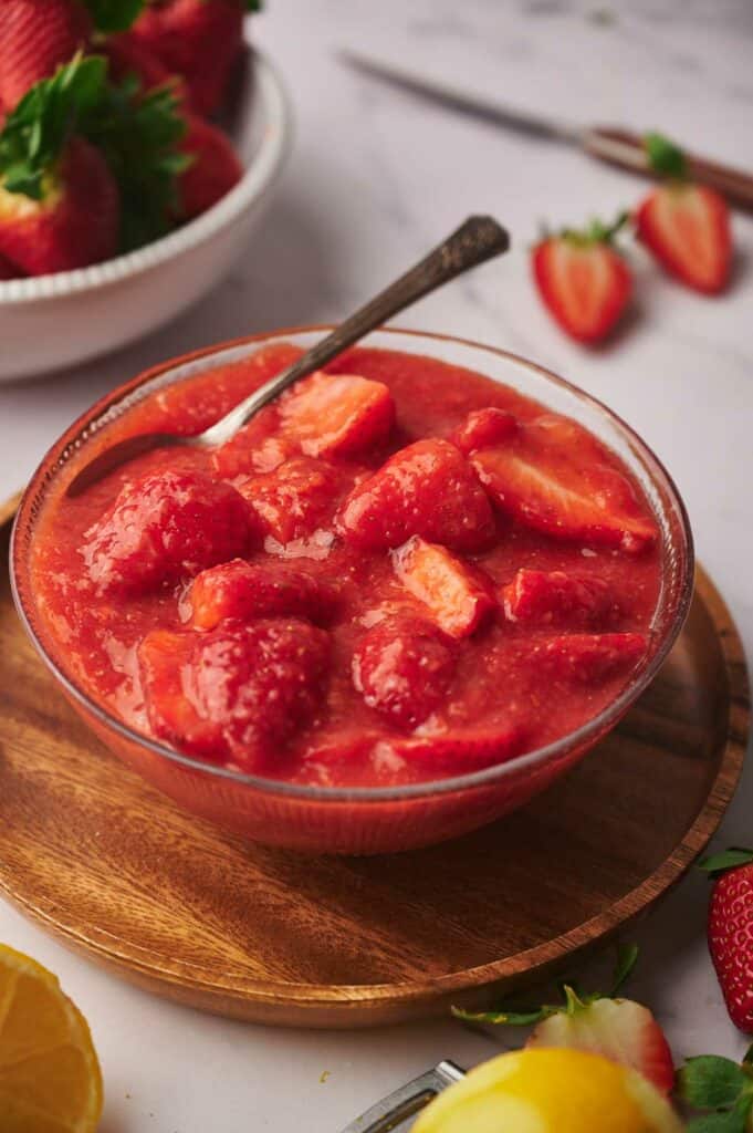 A delicious bowl of strawberry sauce on a wooden plate, ready to eat.
