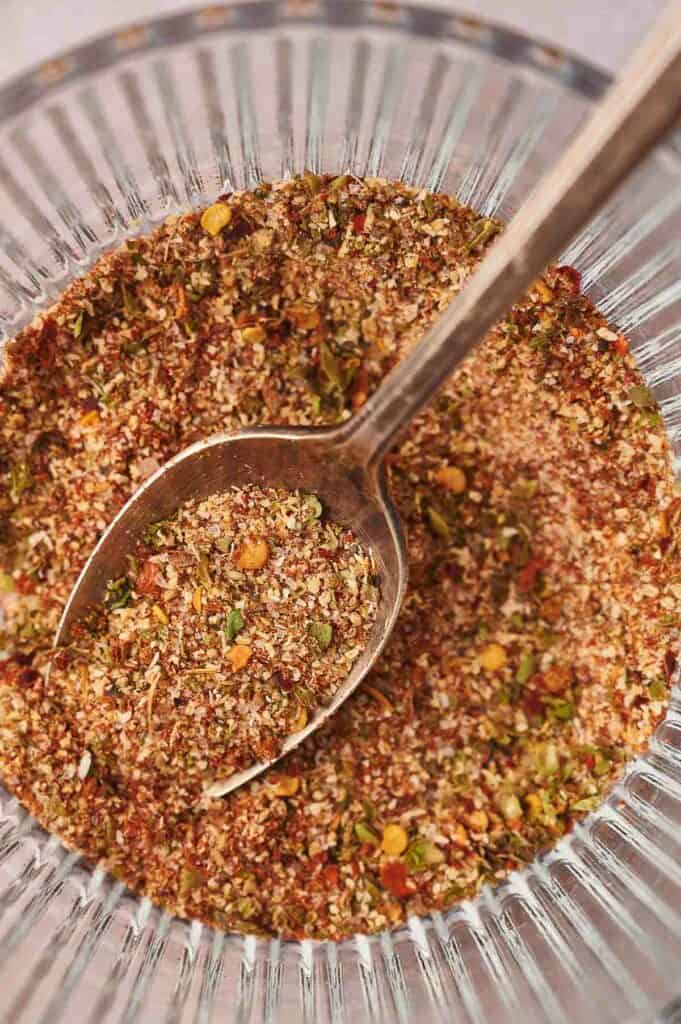 Homemade taco seasoning in a glass dish with a spoon in it.