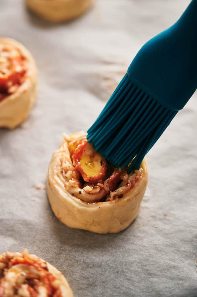 Brushing a pizza roll with olive oil.