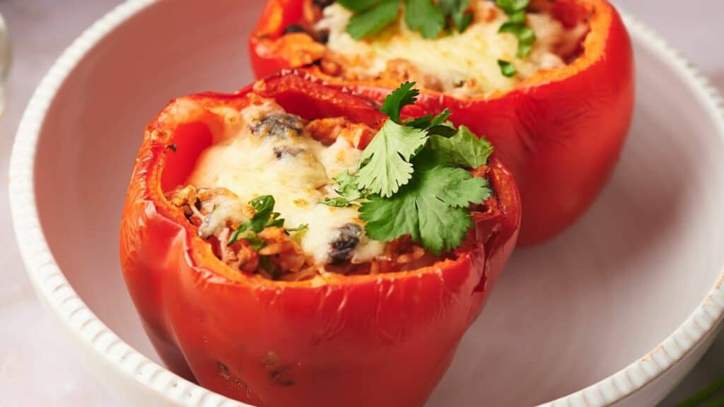 Two stuffed peppers in a white bowl.
