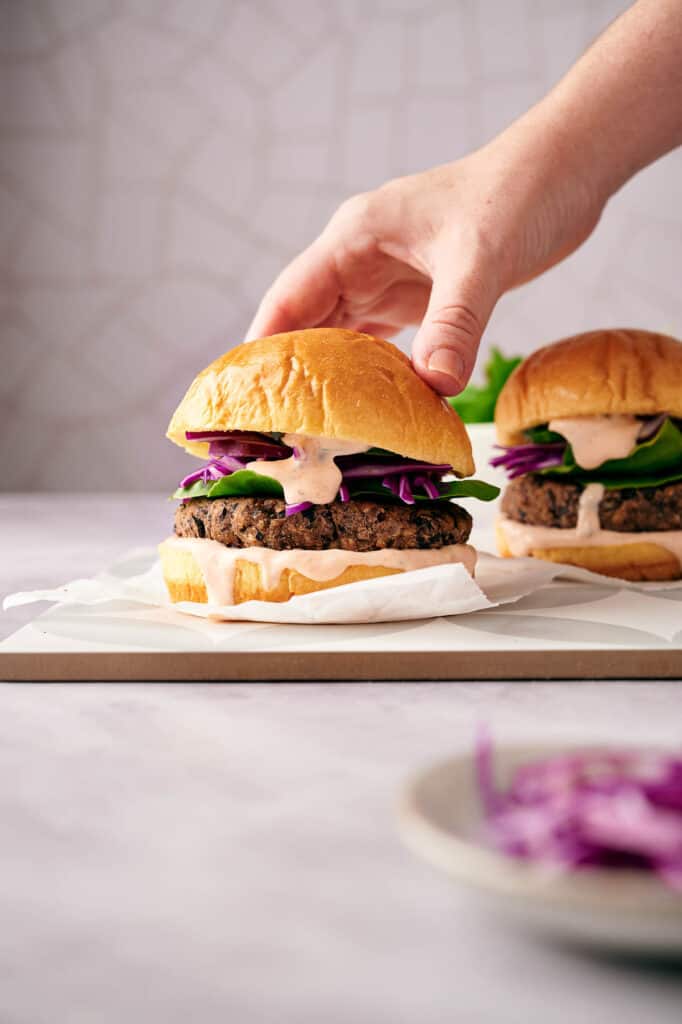 Adding the bun lid to a black bean burger.
