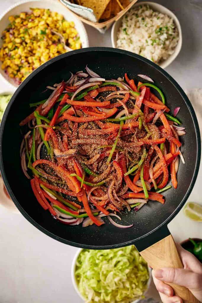 Bell peppers, red onions, and fajita seasoning in a skillet.