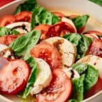 A close up of Caprese salad in a cream bowl.