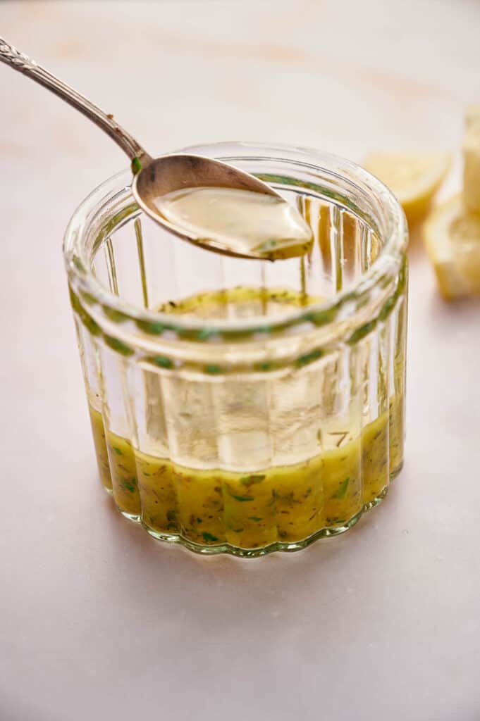 A teaspoon with Italian dressing on it over a jar full.
