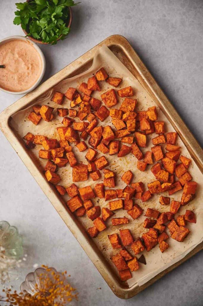 Roasted sweet potato cubes on a baking sheet.