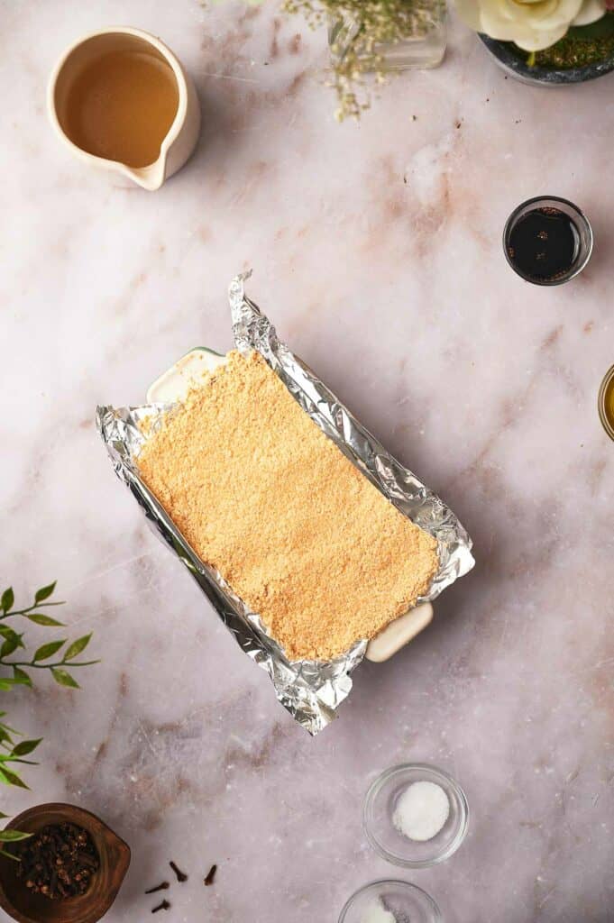 Uncooked vegan ham in tin foil with oil and glaze nearby.