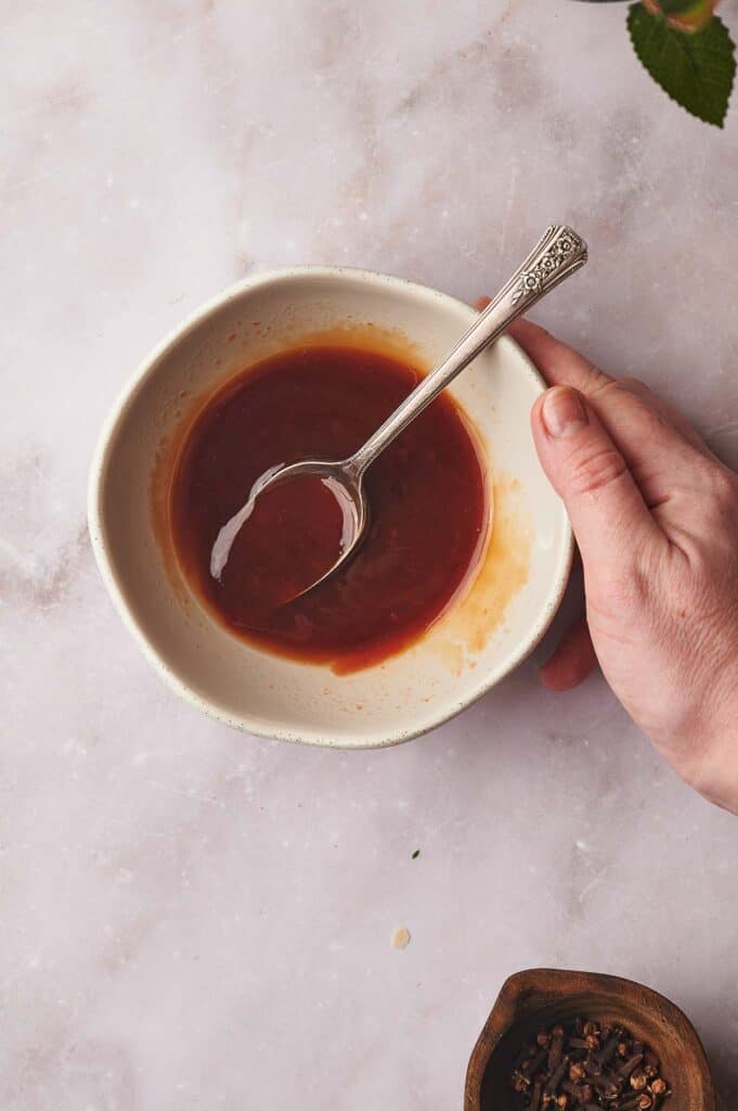 Glaze mixed in a bowl and a hand holding the bowl.