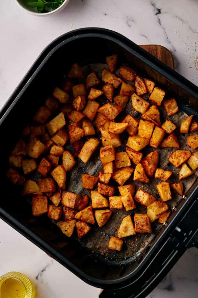 Air fried breakfast potatoes in an air fryer basket.