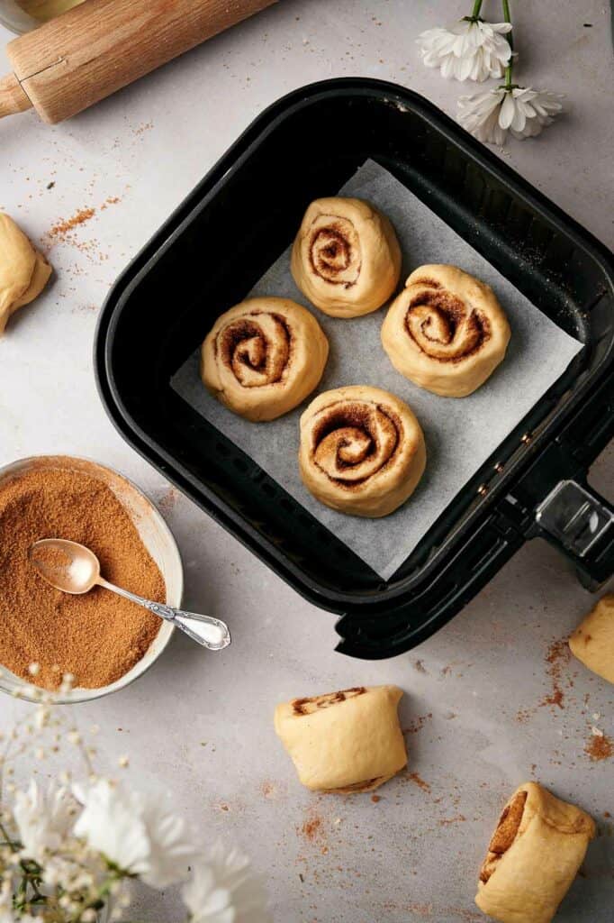 Uncooked cinnamon rolls in an air fryer basket.