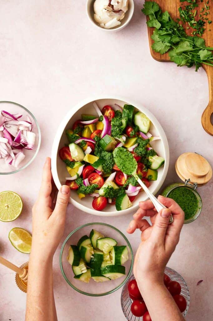Someone spooning on cilantro and lime dressing onto the salad.