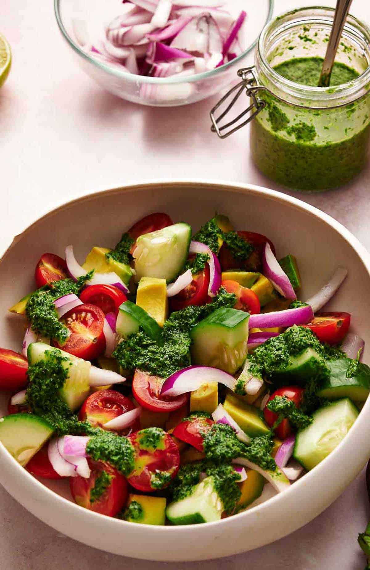 A fresh avocado salad with cilantro lime dressing and a jar of dressing in the background.
