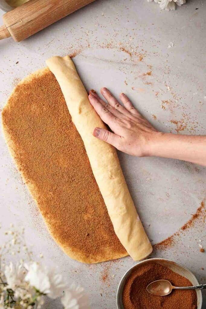 Someone rolling up the cinnamon dough.