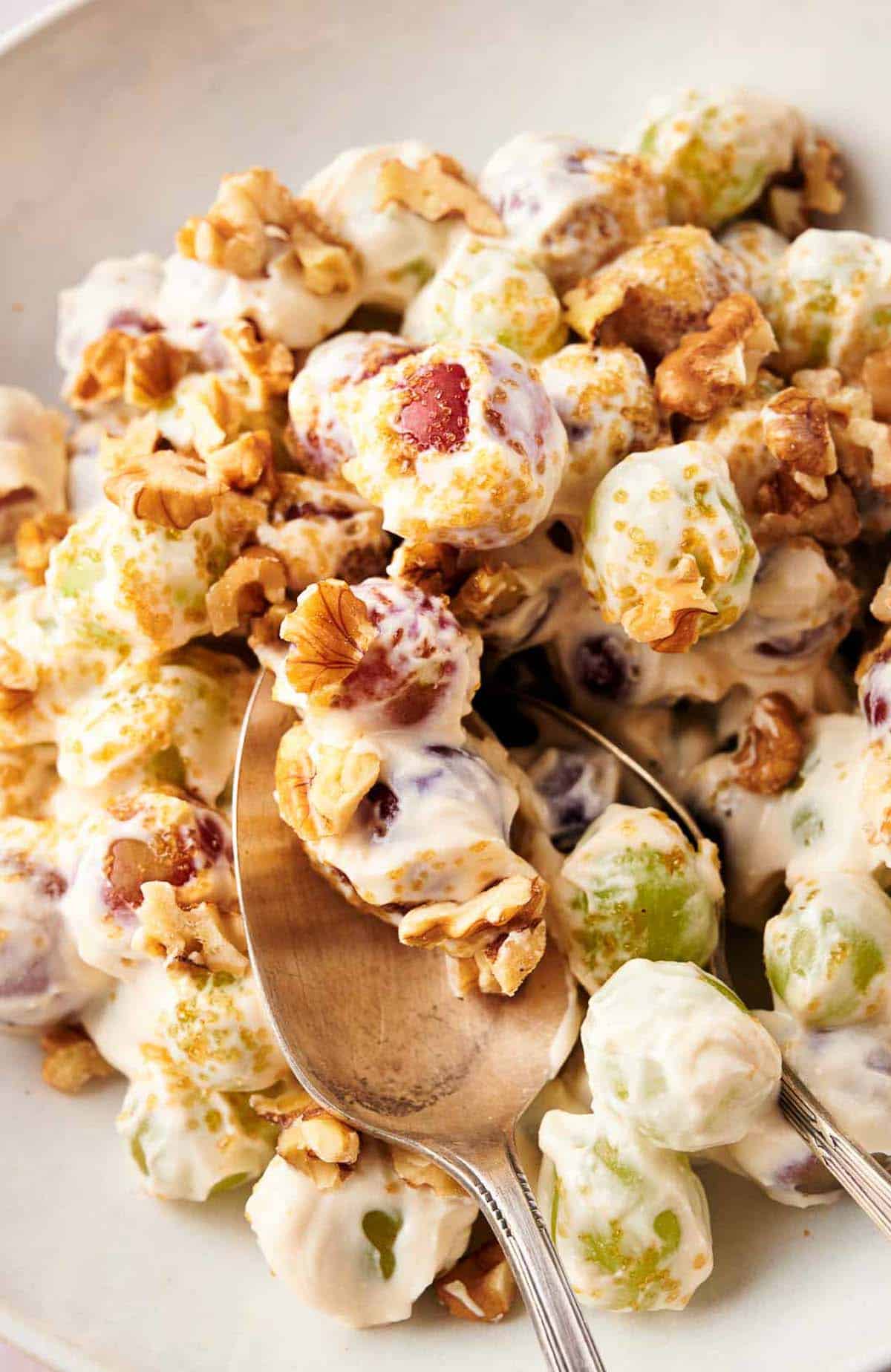 Homemade grape salad in a mixing bowl, with serving spoons.