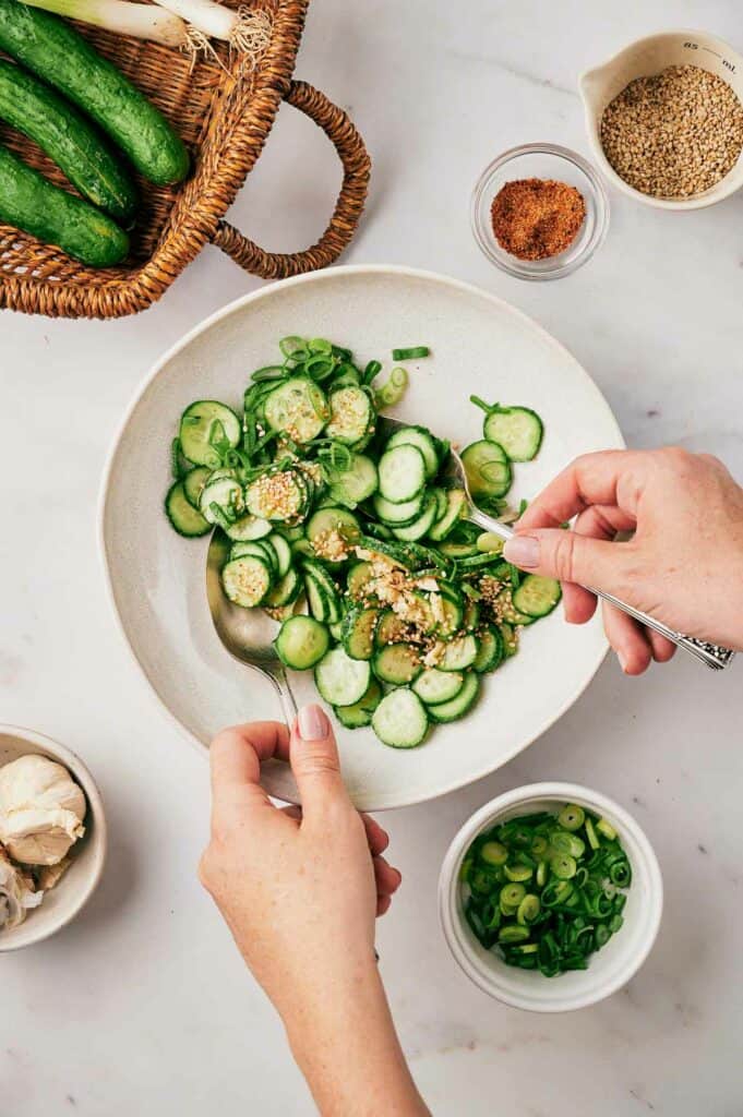 Someone tossing the cucumber slices.