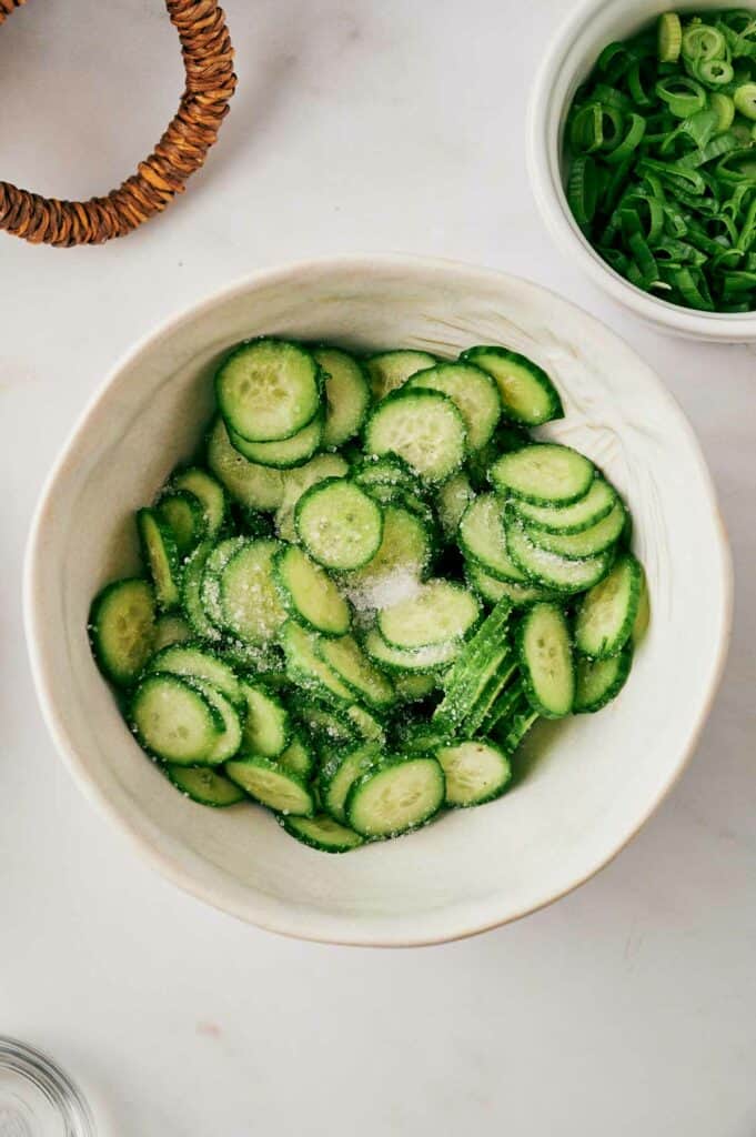 Cucumber slices in a bowl with salt.