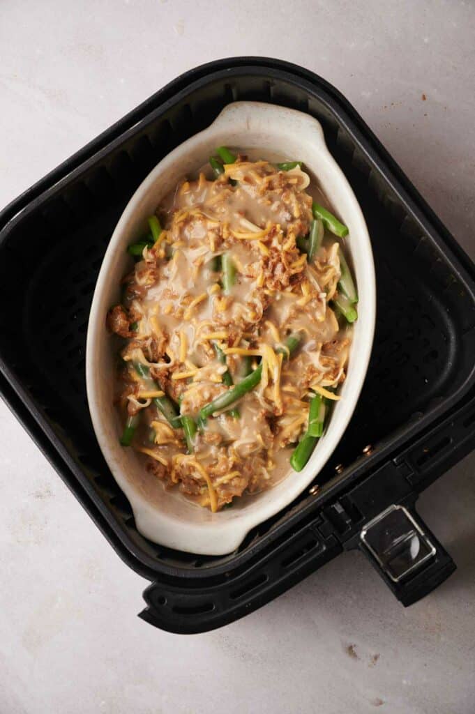 An air fryer cooking a green bean casserole dish.