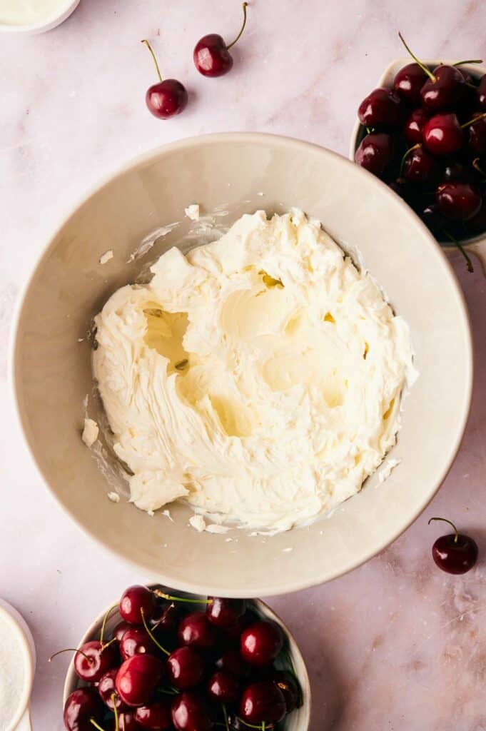 A bowl of whipped cream cheese with cherries in it.