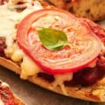 A slice of french bread pizza with tomato and basil.