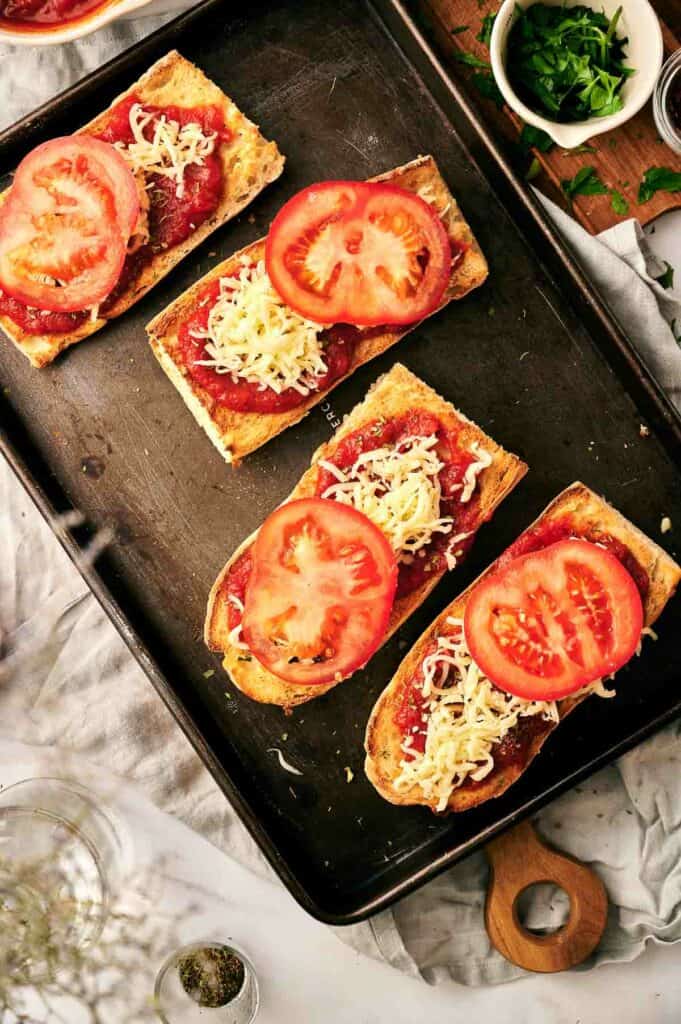 A tray of pizza with tomatoes and cheese on it.