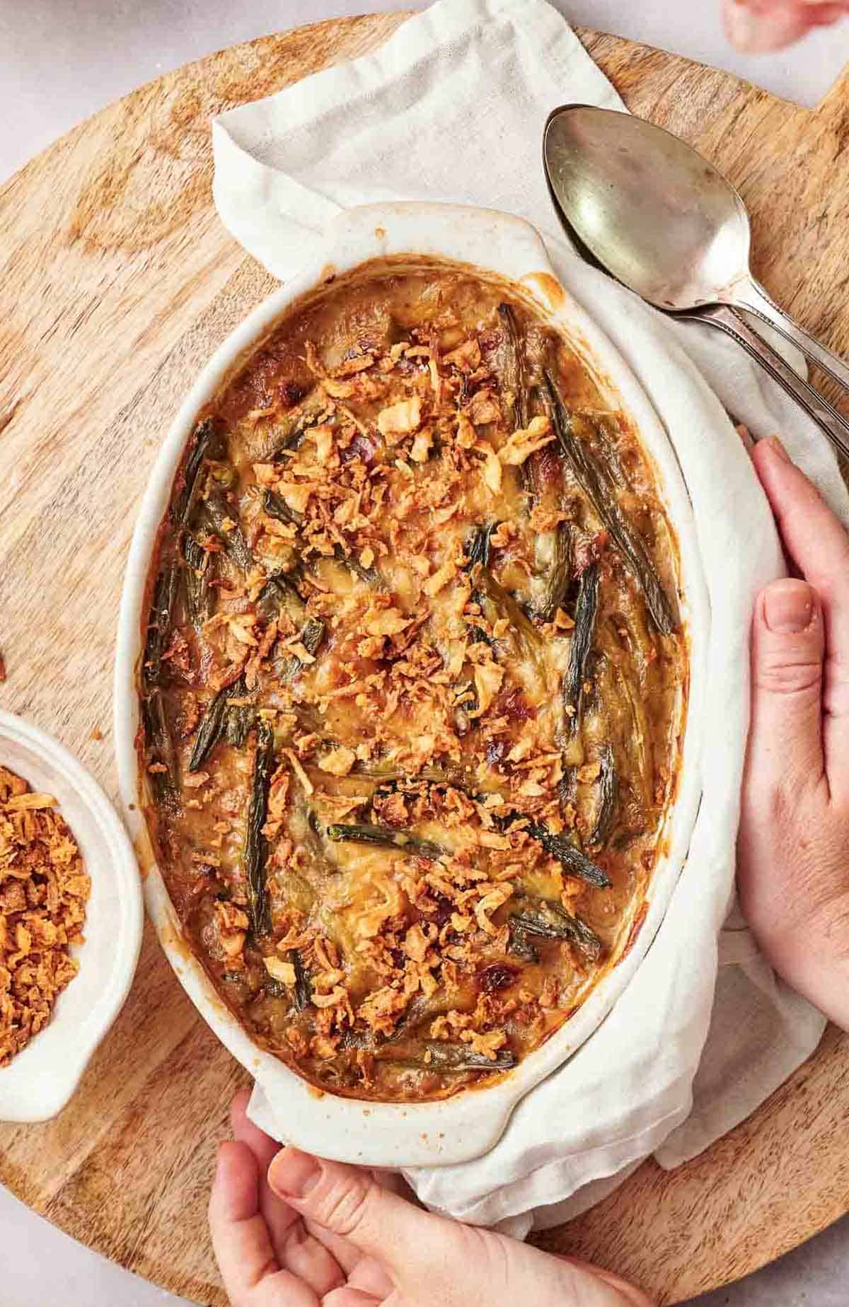 A person holding a casserole dish with a spoon.