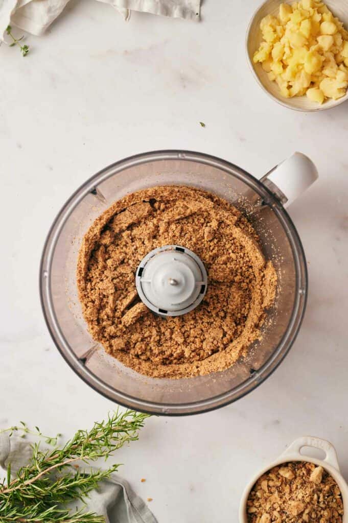 A food processor filled with nut crumbs and other ingredients.