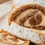 Pumpkin roll on a plate with powdered sugar.